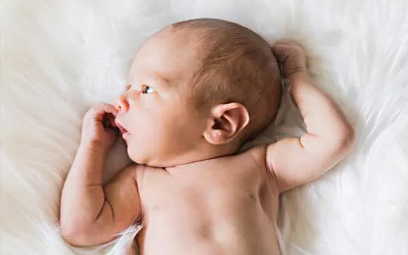 baby laying on it's back with arms up