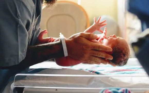 man holding a new born baby in both hands